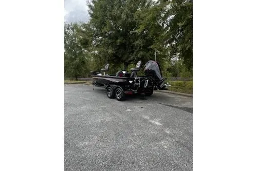 Slide: The Image of 2026 Ranger RT188P boat parked outdoors, rear view with trees in background. - 2
