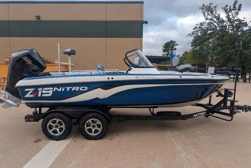 Slide: The Image of 2026 Nitro ZV19 Sport Pro boat on trailer, blue and white design, parked outdoors. - 1