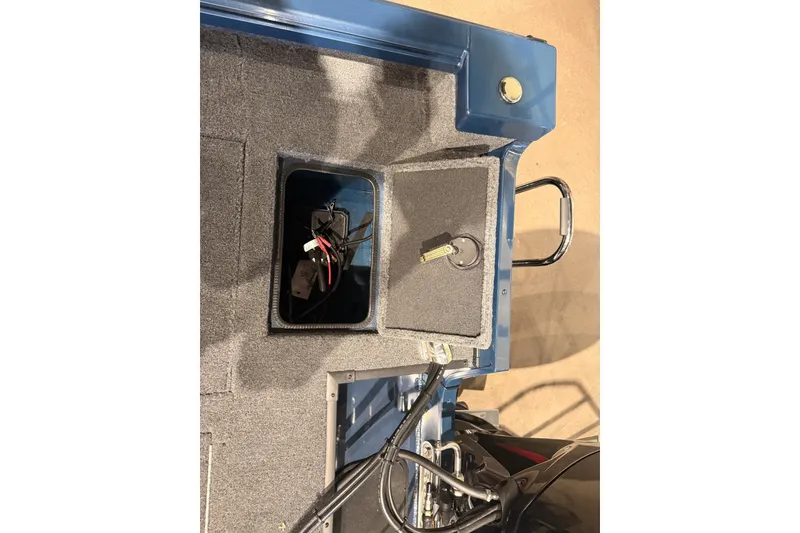 Slide: The Image of 2026 Ranger RT178 boat storage compartment with wiring and key on carpeted surface. - 9