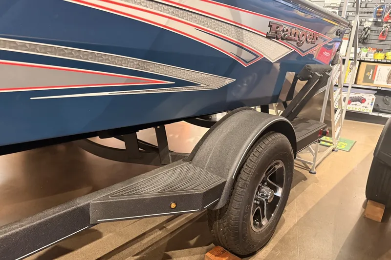 Slide: The Image of 2026 Ranger RT178 boat on trailer, blue with red and silver accents, in showroom. - 2