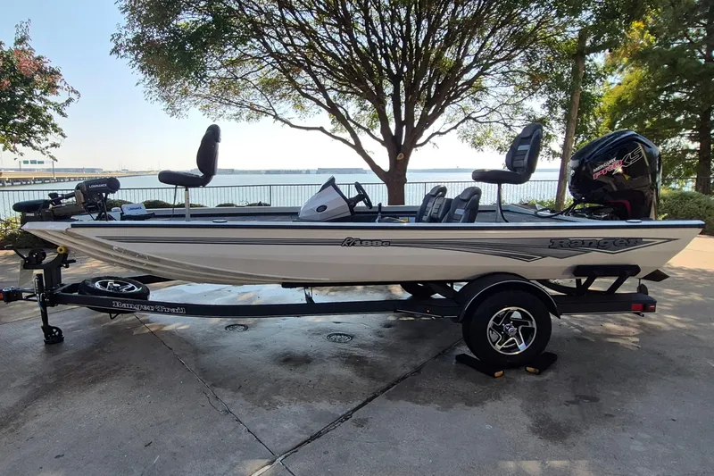 The Image of 2026 Ranger RT188C fishing boat on trailer by lakeside, under tree shade. - 0