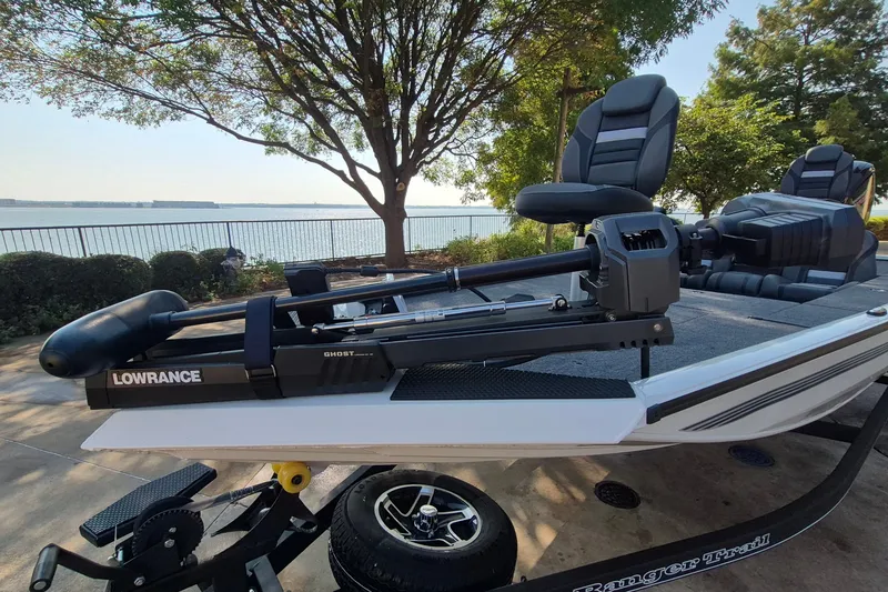 Slide: The Image of 2026 Ranger RT188C boat with Lowrance Ghost trolling motor by a scenic lakeside. - 2
