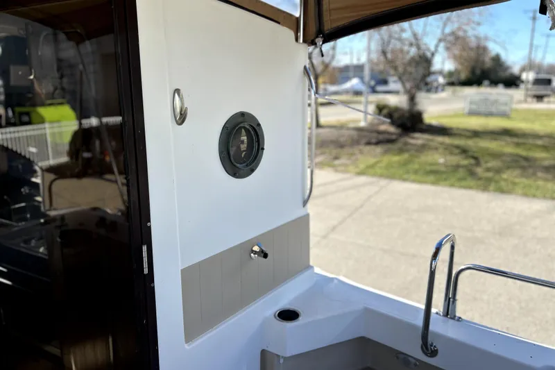 Slide: The Image of 2013 Ranger Tugs R-27 boat interior with porthole and railing, docked outdoors. - 11