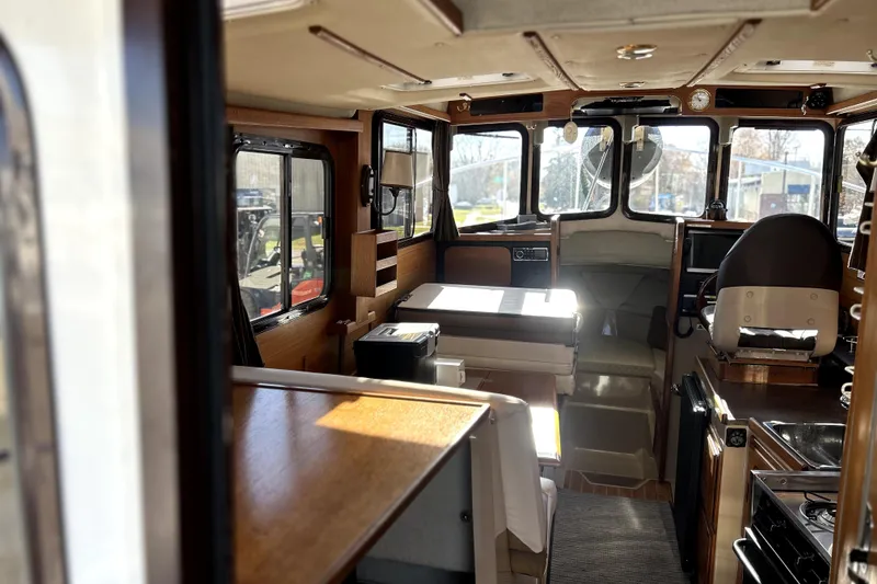 Slide: The Image of Interior of 2013 Ranger Tugs R-27 boat, featuring cozy seating and wooden finishes. - 12