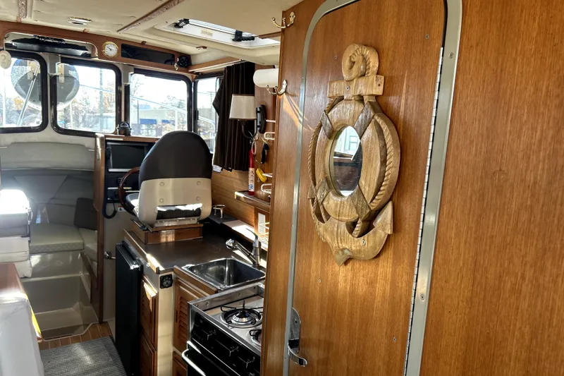 Slide: The Image of Interior of 2013 Ranger Tugs R-27 boat with wooden decor and compact kitchen area. - 13