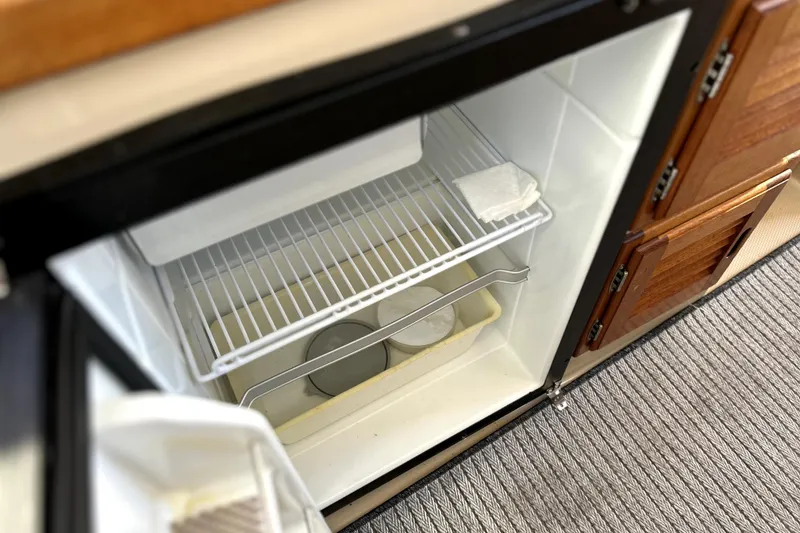 Slide: The Image of Open refrigerator inside 2013 Ranger Tugs R-27 boat, showing interior shelves and storage. - 16