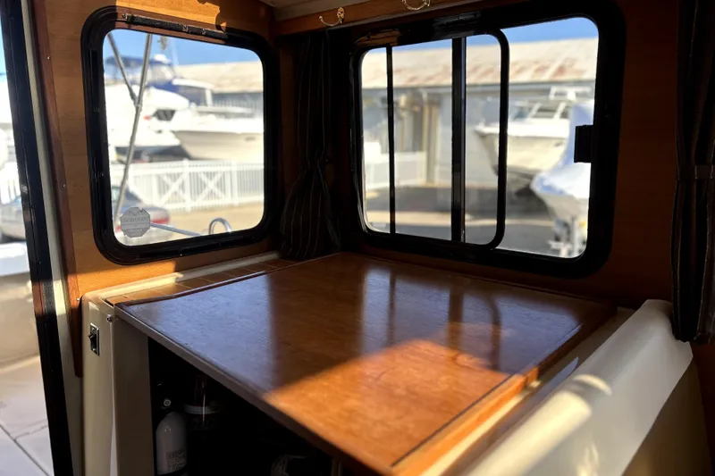 Slide: The Image of Interior of 2013 Ranger Tugs R-27 with wooden table and marina view. - 17