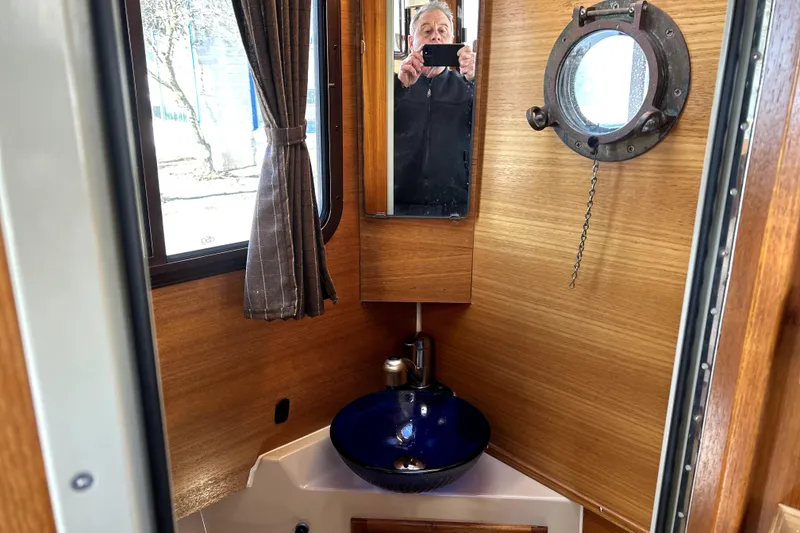 Slide: The Image of 2013 Ranger Tugs R-27 interior with wooden finish, porthole, and blue sink. - 42