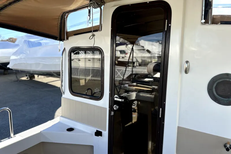Slide: The Image of 2013 Ranger Tugs R-27 boat exterior with open cabin door and window. - 7