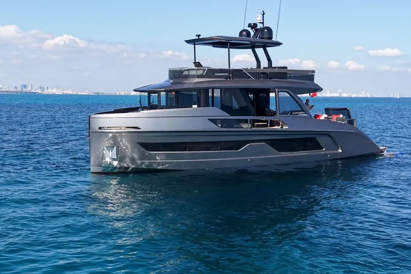 Slide: The Image of 2024 Explorer EX62 yacht on calm blue ocean with city skyline in background. - 2