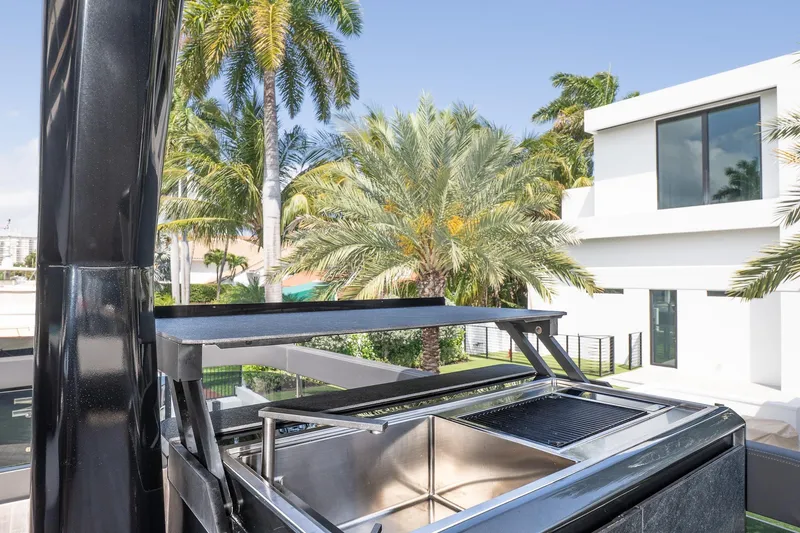 Slide: The Image of Modern outdoor kitchen with grill, surrounded by palm trees and contemporary architecture. Explorer EX62, 2024. - 38