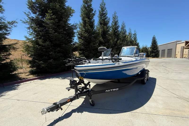 Slide: The Image of 2026 Nitro ZV19 Sport Pro boat on trailer, parked outdoors, surrounded by trees. - 6