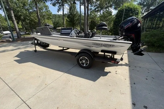 The Image of 2026 Ranger RT188 boat on trailer, parked outdoors, surrounded by trees. - 0
