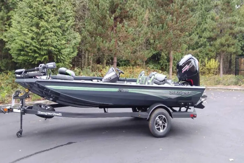 Slide: The Image of 2026 Ranger RT188 fishing boat on trailer, parked near forested area. - 100