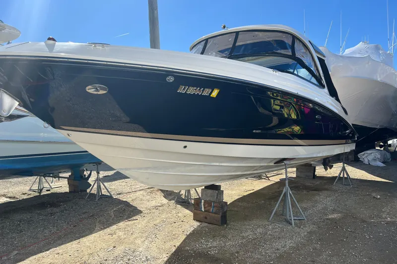 Slide: The Image of 2015 Sea Ray 350 SLX boat on stands, blue and white hull, sunny day. - 3