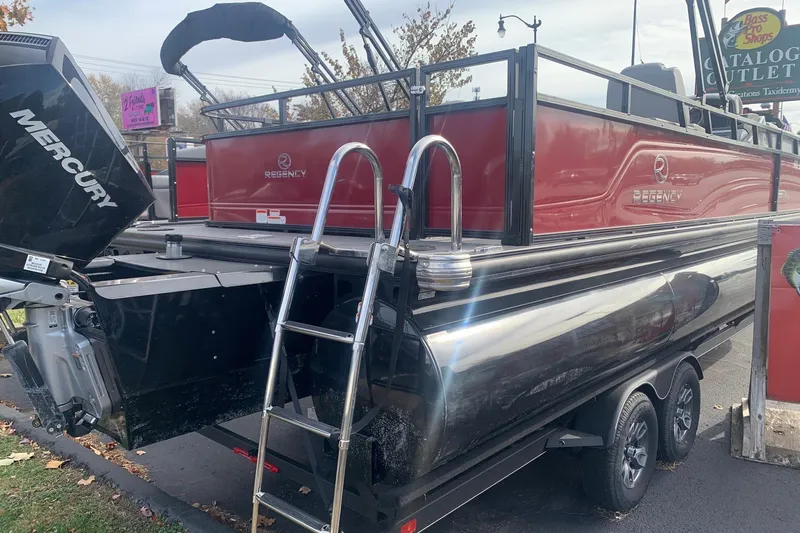 The Image of 2024 Regency 250 DL3 pontoon boat with Mercury engine, parked on a trailer. - 1