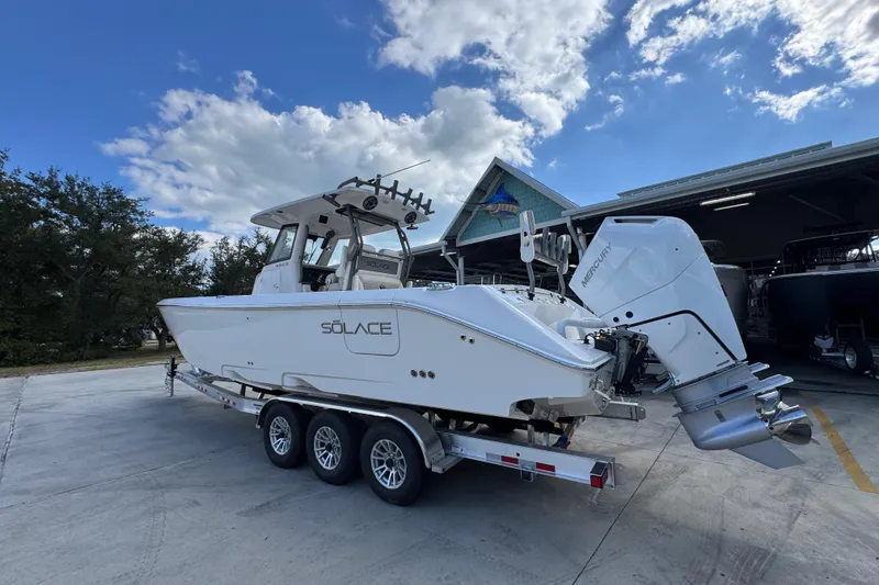 Slide: The Image of 2026 Solace 32 CS boat on trailer, parked outdoors under a blue sky. - 15