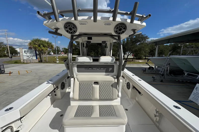 Slide: The Image of 2026 Solace 32 CS boat interior with seating and rod holders, parked outdoors. - 44