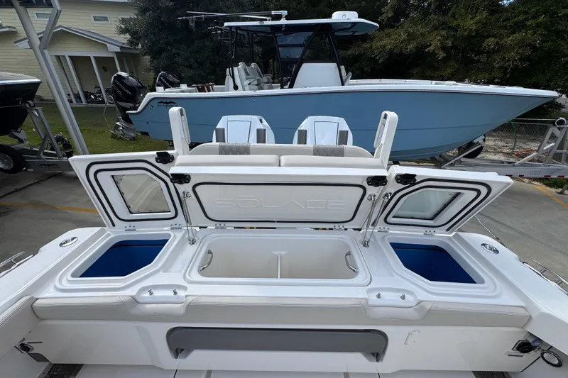 Slide: The Image of 2026 Solace 32 CS boat with open storage compartments, docked near a blue vessel. - 50