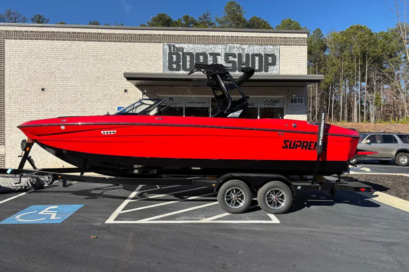 The Image of 2026 Supreme S240 boat in vibrant red on a trailer outside a shop. - 0