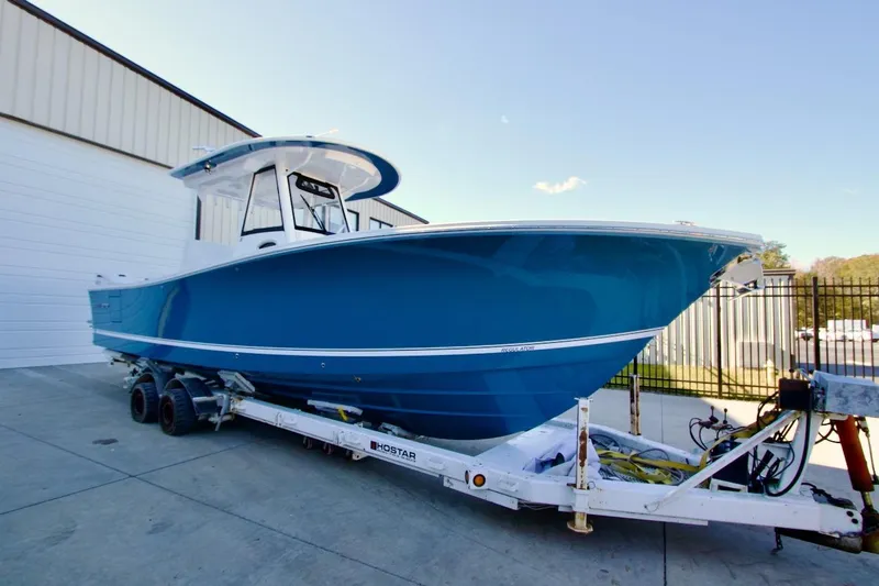 The Image of 2026 Regulator 31 boat in blue on a trailer, parked outside a warehouse. - 0
