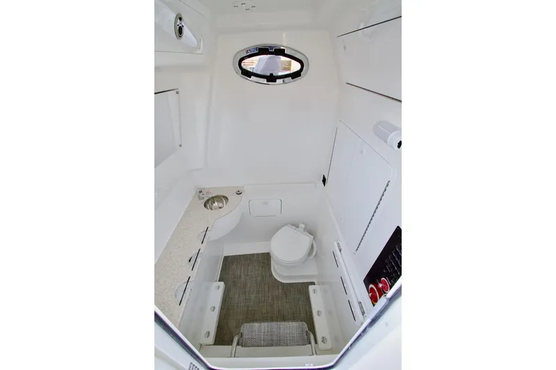 Slide: The Image of 2026 Regulator 31 boat interior with compact bathroom, featuring a toilet, sink, and window. - 18