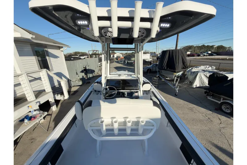 Slide: The Image of 2026 Tidewater 2300 Carolina Bay boat with T-top and rod holders, parked outdoors. - 7