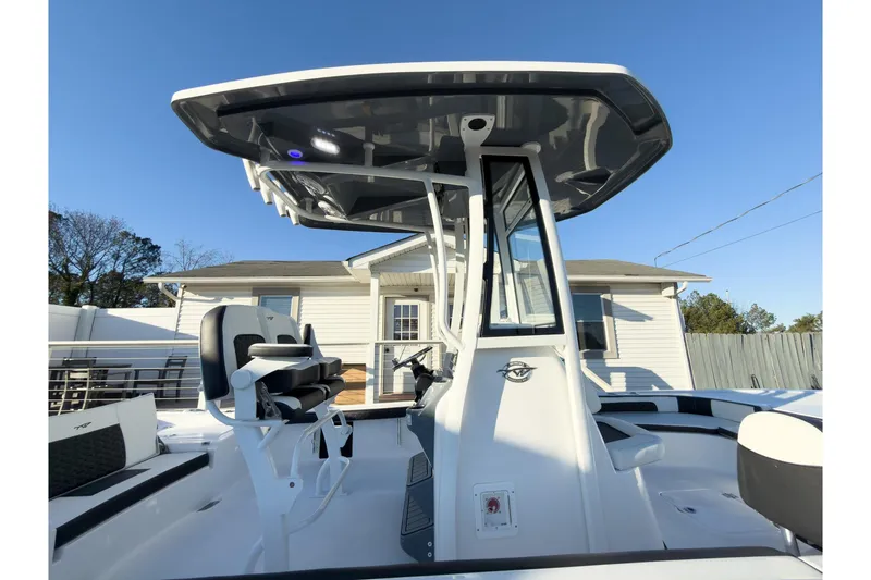 Slide: The Image of 2026 Tidewater 2300 Carolina Bay boat with T-top and seating, docked near a house. - 9