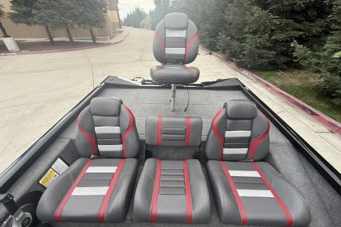 Slide: The Image of 2021 Ranger RT178 boat interior with gray and red seats, parked on a paved road. - 17