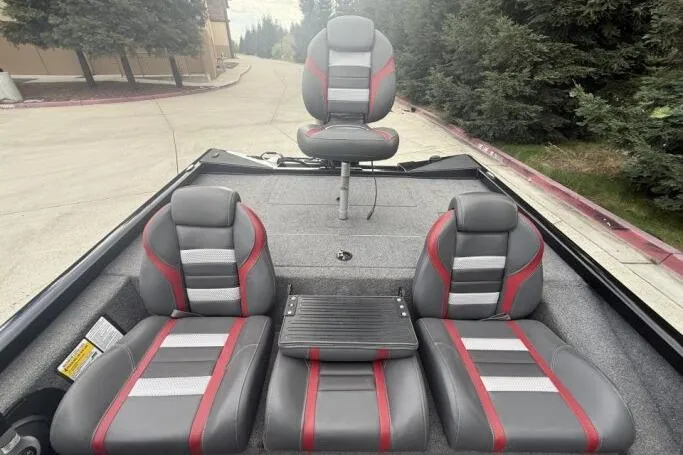 Slide: The Image of 2021 Ranger RT178 boat interior with gray and red seating, surrounded by trees. - 18
