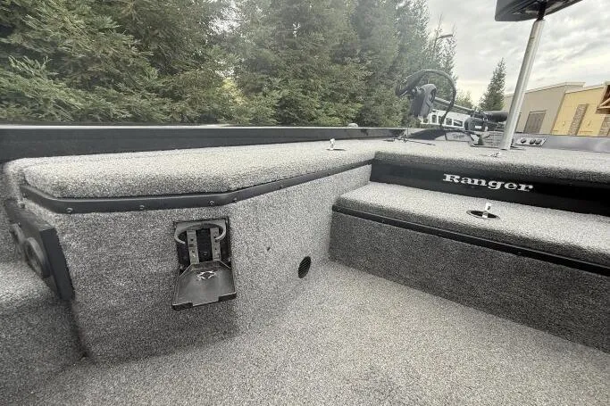 Slide: The Image of 2021 Ranger RT178 boat interior with carpeted deck and steering wheel, surrounded by trees. - 22
