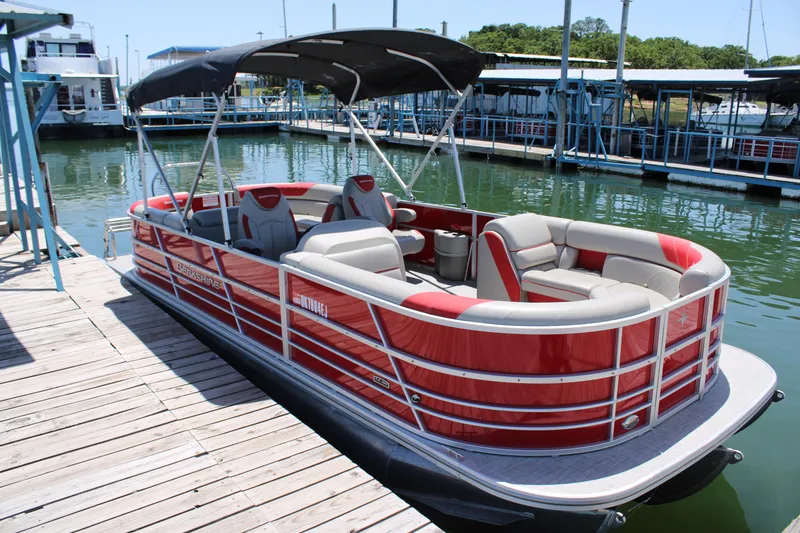 The Image of 2024 Berkshire 24RFX LE pontoon boat docked, featuring red and gray seating under a canopy. - 0