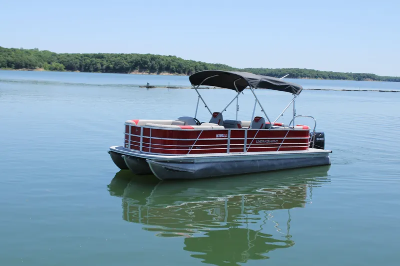 Slide: The Image of 2024 Berkshire 24RFX LE pontoon boat on a calm lake under clear skies. - 1
