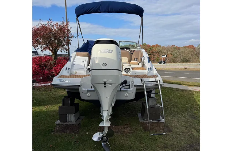 Slide: The Image of 2021 Crownline Eclipse E255 XS boat with outboard motor and ladder, displayed outdoors. - 1