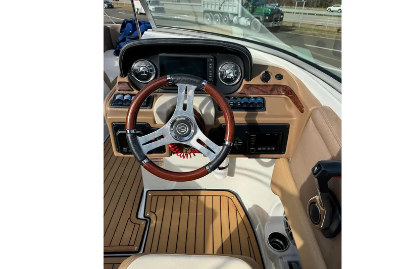 Slide: The Image of 2021 Crownline Eclipse E255 XS boat dashboard with wood-accented steering wheel and modern controls. - 2
