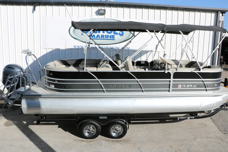 Slide: The Image of 2023 Sylvan Mirage X X3 Party Fish pontoon boat on trailer, parked outside a marine shop. - 8