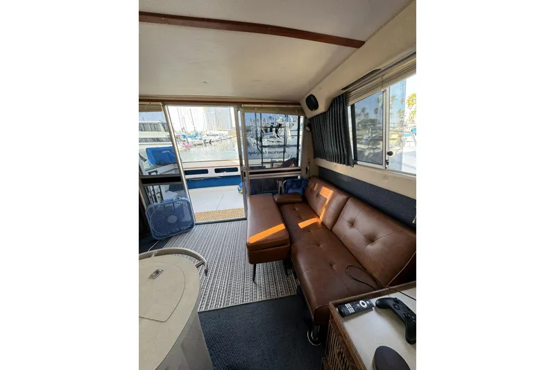 Slide: The Image of Interior of 1985 Sea Ray 340 Sedan Bridge with leather sofa and marina view. - 3