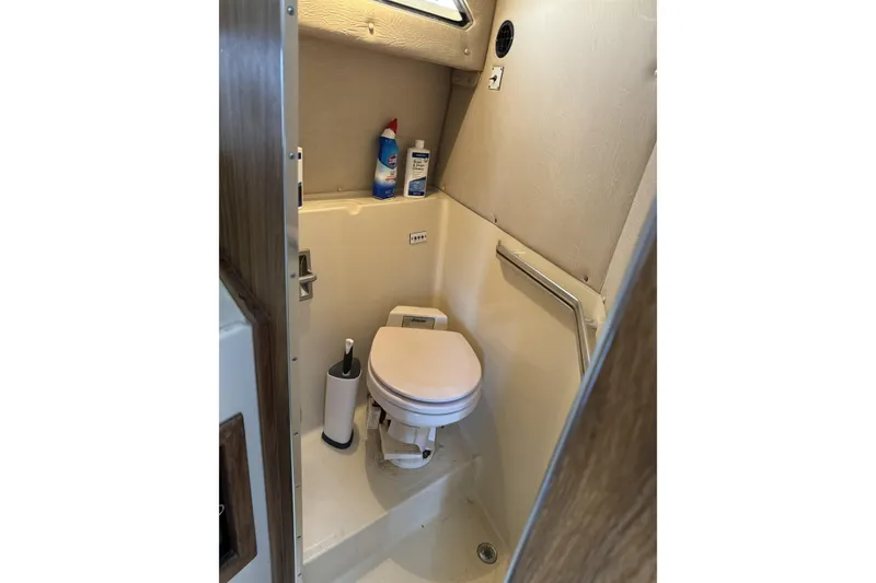 Slide: The Image of 1985 Sea Ray 340 Sedan Bridge bathroom with toilet and cleaning supplies. - 6