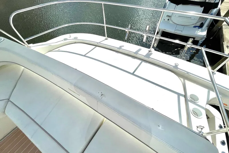 Slide: The Image of 2005 Silverton 43 Sport Bridge yacht deck with railing and seating, docked by the water. - 11