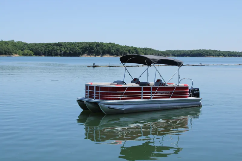 Slide: The Image of 2024 Berkshire 24RFX LE pontoon boat on a serene lake. - 2