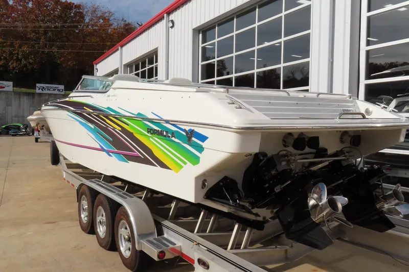 Slide: The Image of 1999 Formula 382 FASTech boat with colorful graphics on a trailer outside a garage. - 5