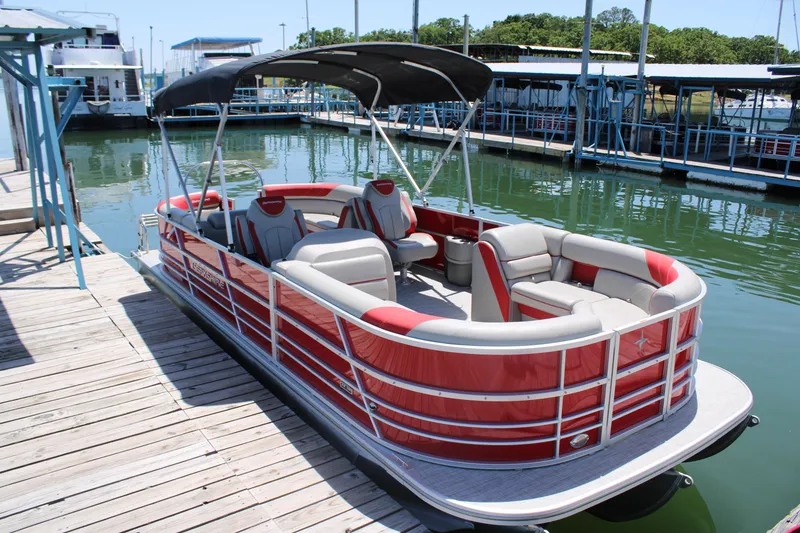 Slide: The Image of 2024 Berkshire 24RFX LE pontoon boat docked, featuring red and white seating and canopy. - 3