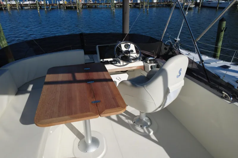 Slide: The Image of 2023 Beneteau Swift Trawler 35 helm with wooden table and captain's chair, dockside view. - 20
