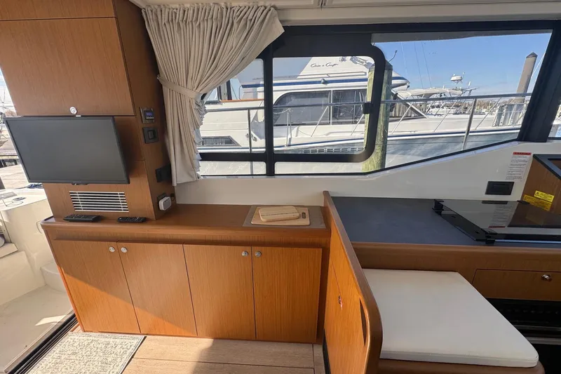 Slide: The Image of Interior of 2023 Beneteau Swift Trawler 35 with wood cabinetry and window view. - 44