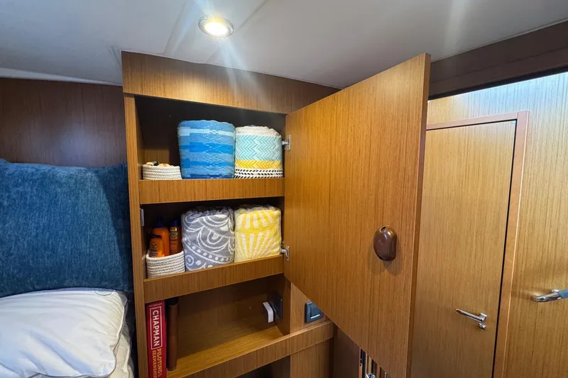 Slide: The Image of Interior of 2023 Beneteau Swift Trawler 35 with open wooden cabinet and neatly arranged towels. - 50