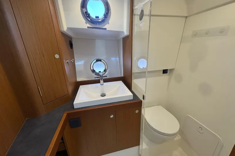 Slide: The Image of Bathroom interior of 2023 Beneteau Swift Trawler 35, featuring sink, toilet, and porthole window. - 51