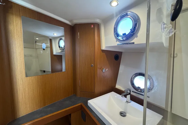 Slide: The Image of 2023 Beneteau Swift Trawler 35 bathroom with wood accents and porthole windows. - 52