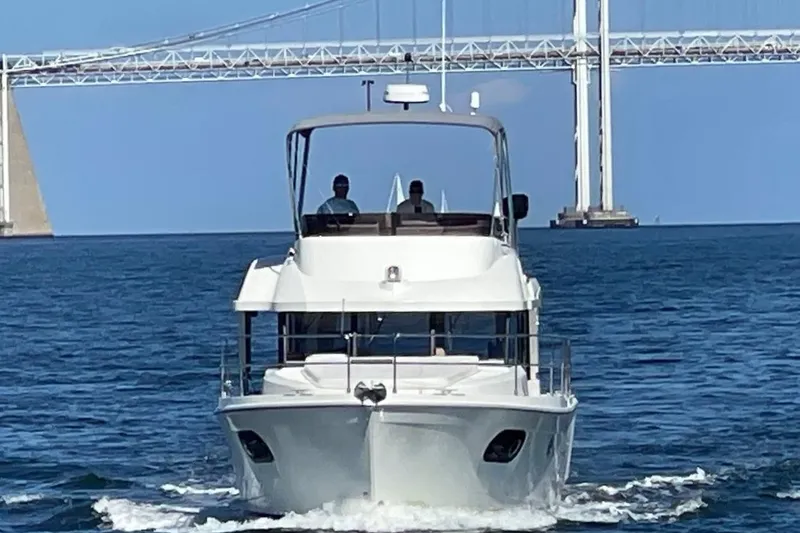 Slide: The Image of 2023 Beneteau Swift Trawler 35 cruising under a bridge on open water. - 6