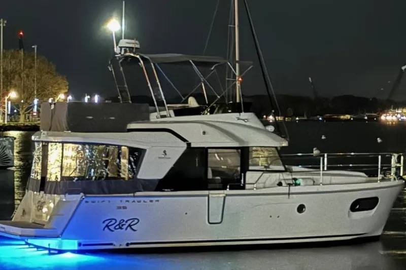 Slide: The Image of 2023 Beneteau Swift Trawler 35 at night, illuminated with blue lights. - 8