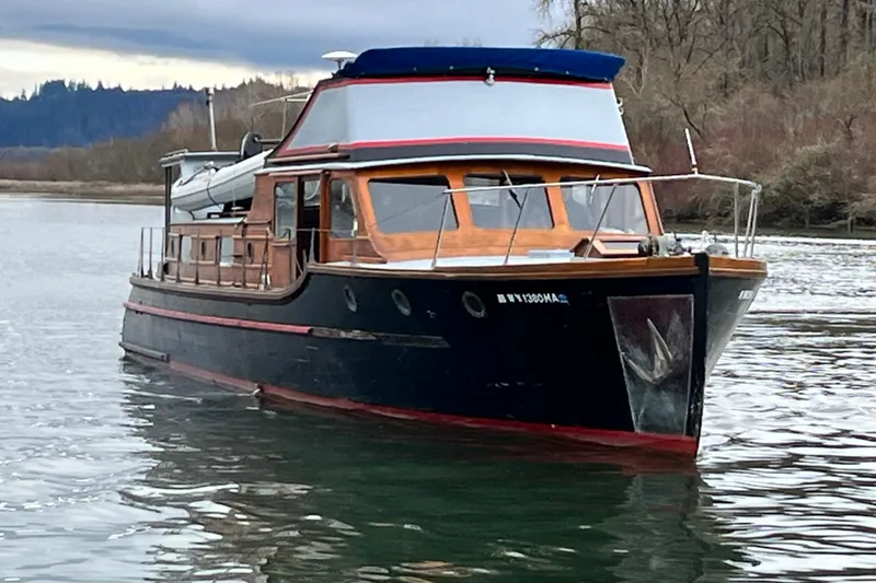 The Image of 1943 Custom Shain-Monk Bridgedeck Cruiser on serene water, surrounded by trees. - 0